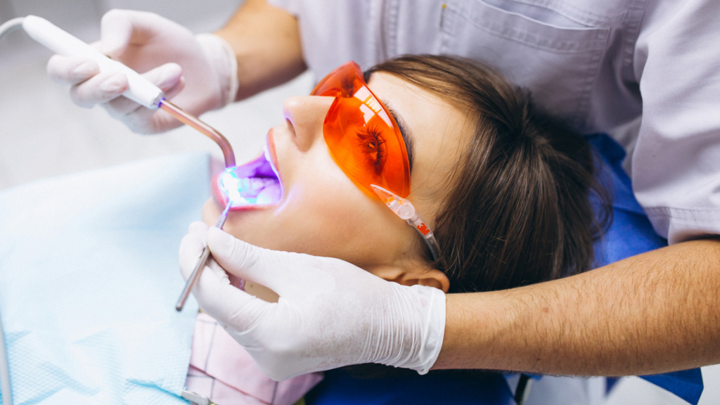 Dentista aplicando resina dental a un paciente en DentPrax